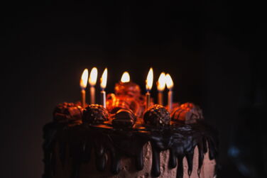 Torte mit Kerzen vor dunkelm Hintergrund. Foto von Duncan Kidd auf Unsplash